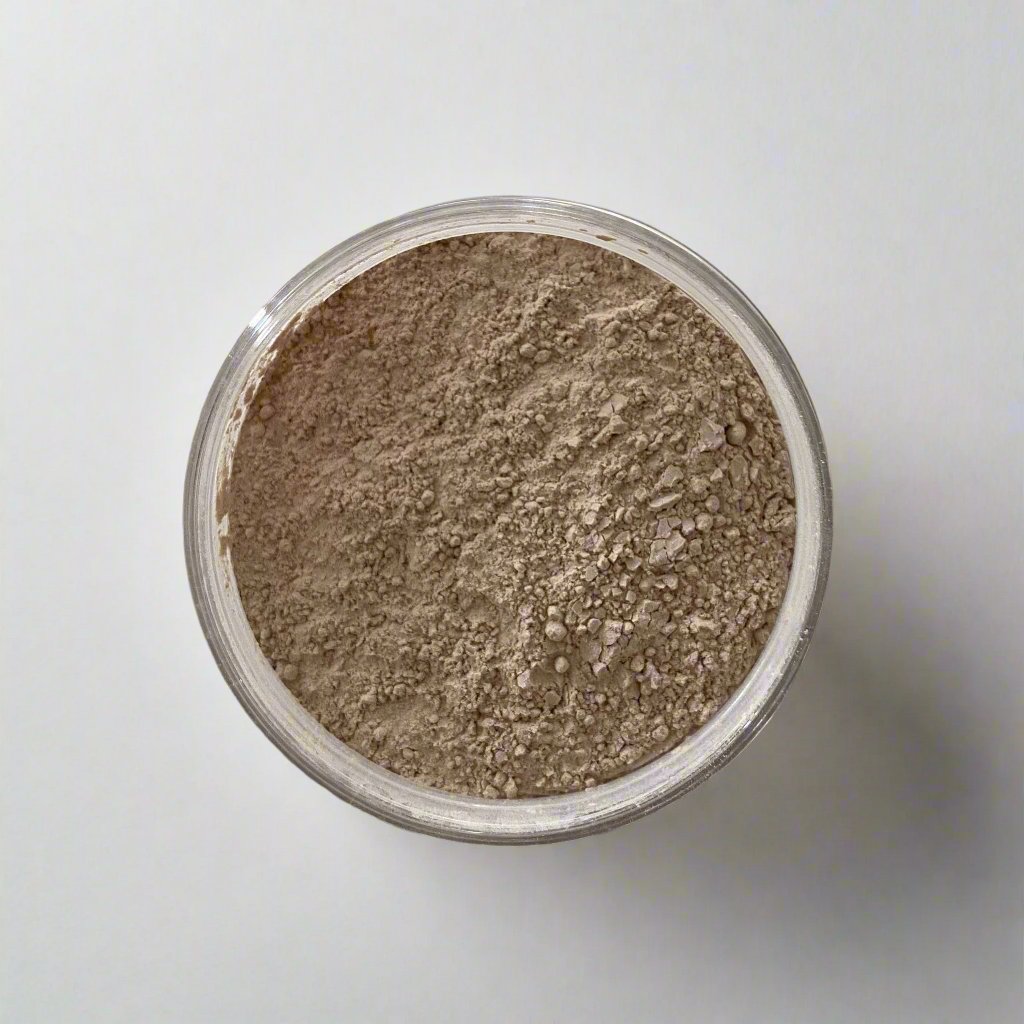 Beldies Rhassoul clay jar opened, revealing the soft, fine powder, which can be mixed with water to create a nourishing facial mask.